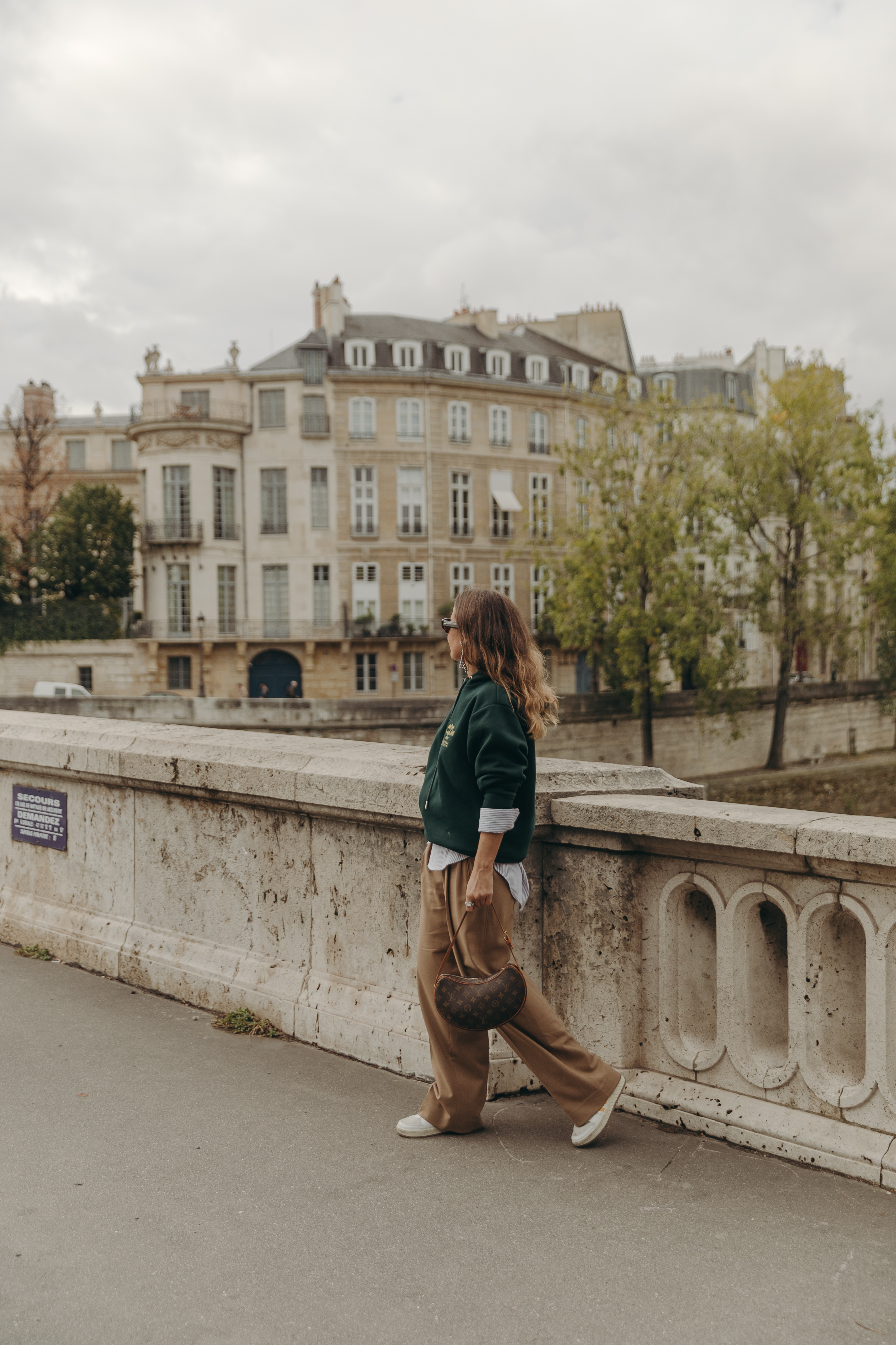 Sara from Collage Vintage at Paris Fashion Week wearing a oversize green sweatshirt, camel trousers, Louis Vuitton vintage bag and sneakers.